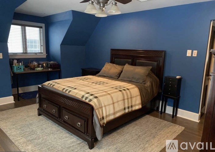 A bedroom with blue walls and a bed with a plaid comforter.