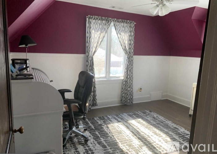 A room with a chair and a window with curtains.