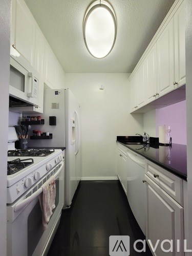 A kitchen with white cabinets and a black counter top.