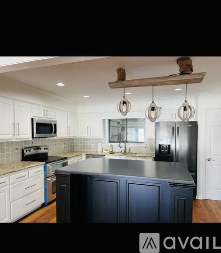 A kitchen with a dark island and white cabinets.
