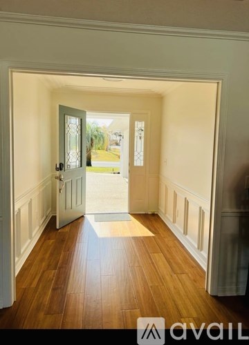 A hallway with a wooden floor and white walls.