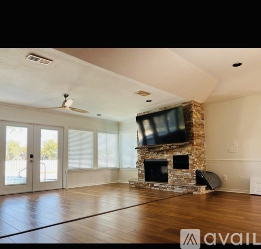 A living room with a stone fireplace and a flat screen TV mounted above it.
