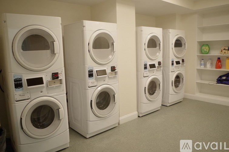 A row of white front load washing machines in a laundry room.