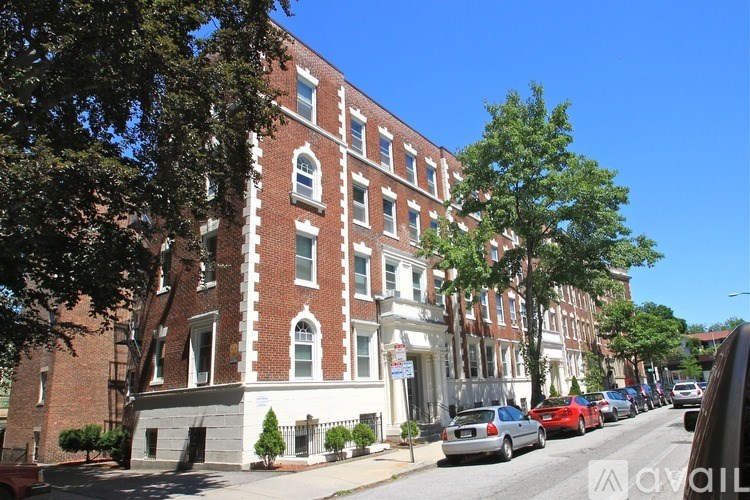 A street view of a red brick building with a tree in front of it.