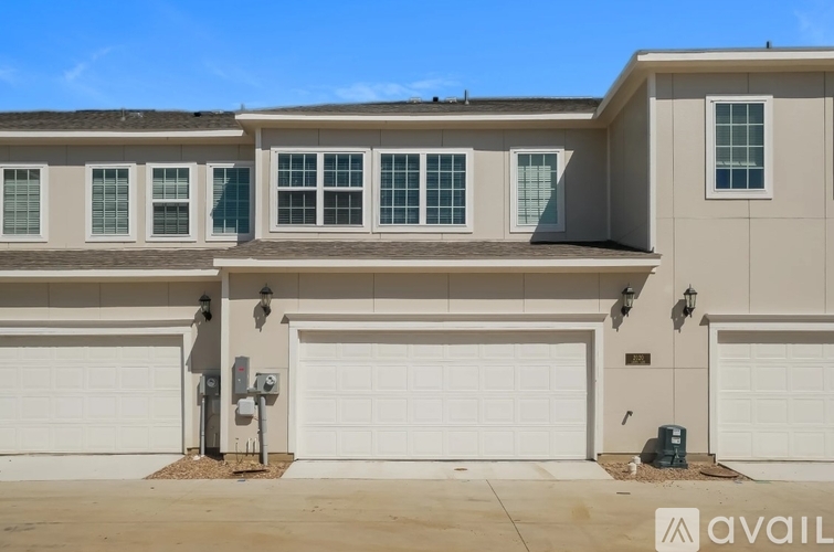 A house with a beige facade and white garage doors.