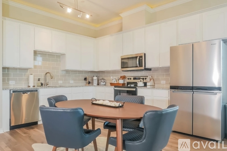 A kitchen with a table and chairs in the foreground and a refrigerator in the background.