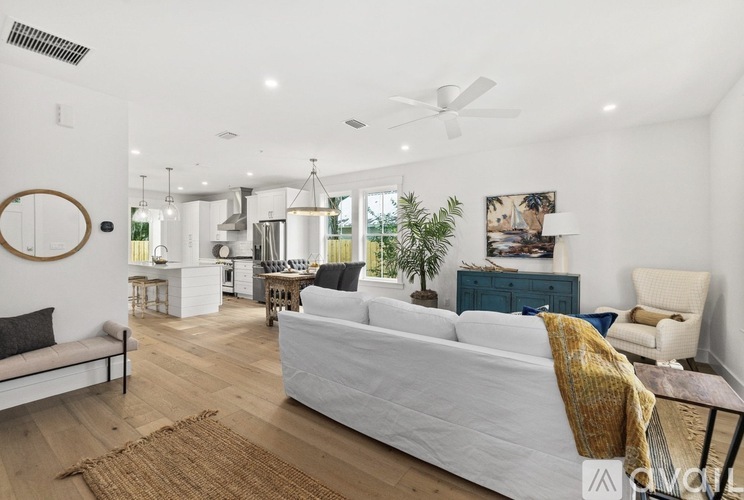 A living room with a white couch and a wooden floor.