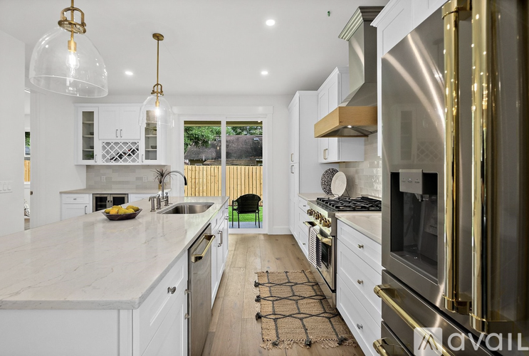 A modern kitchen with white cabinets and a marble countertop.