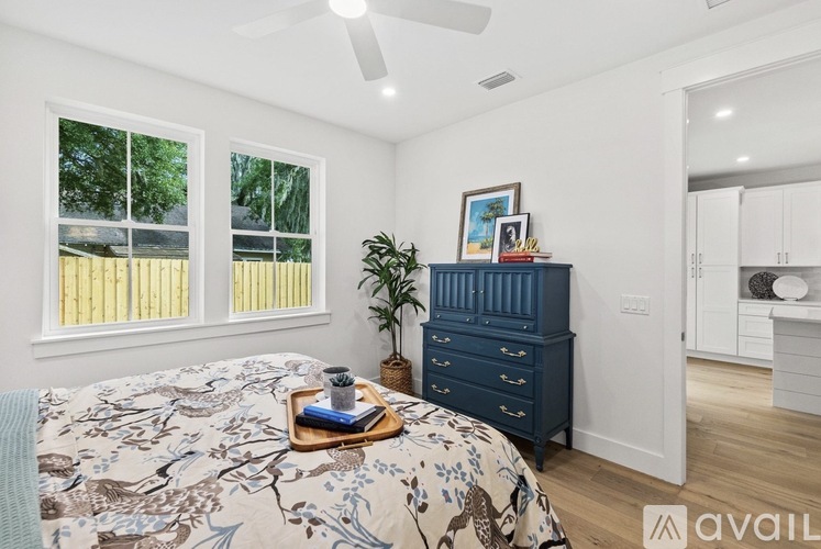 A bedroom with a bed, dresser, and ceiling fan.