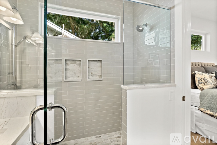 A bathroom with a glass shower door and a white tub.