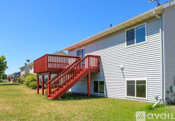 A red staircase leads to a balcony on a white house.