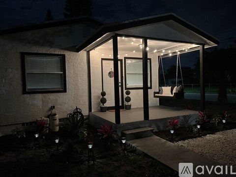 A house with a lit up front porch at night.