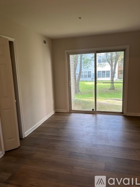 A room with wooden floors and a sliding glass door leading to a green outdoor area.