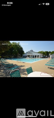 A pool with green lounge chairs and a white building in the background.