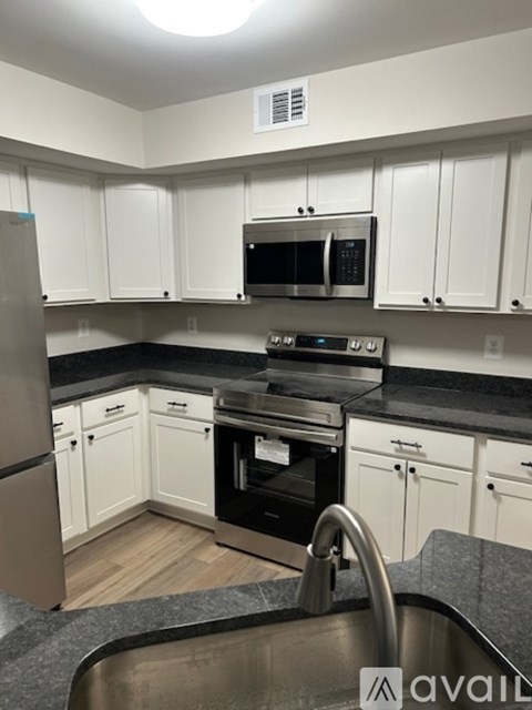 A kitchen with white cabinets and black countertops.