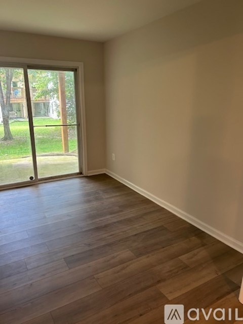 A room with wooden flooring and a sliding glass door leading to a grassy area.