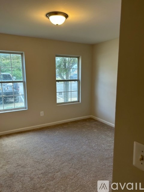 A room with a carpeted floor and two windows.