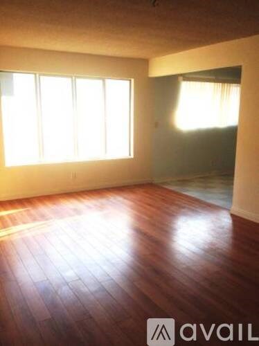 A room with wooden floors and windows letting in sunlight.