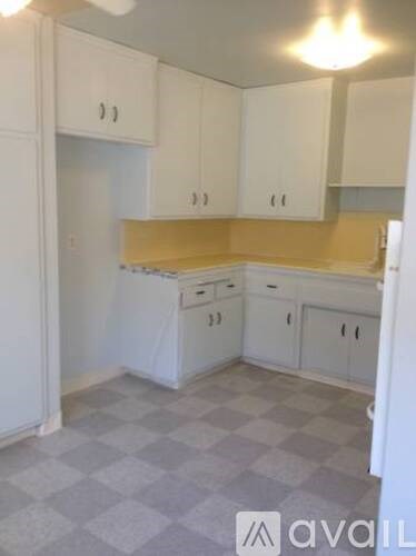 A kitchen with white cabinets and a checkered floor.