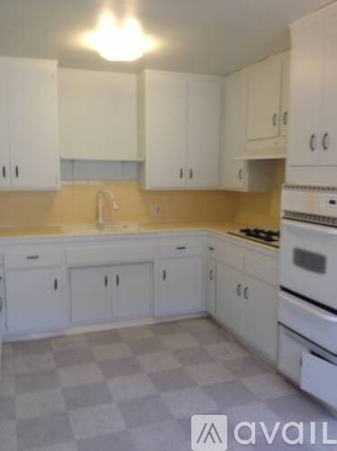A kitchen with white cabinets and a checkered floor.