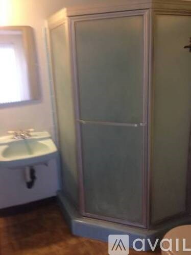 A tall, narrow medicine cabinet with a glass door stands in a bathroom.