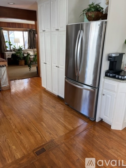 A wooden dining table with four chairs and a clock on the wall.