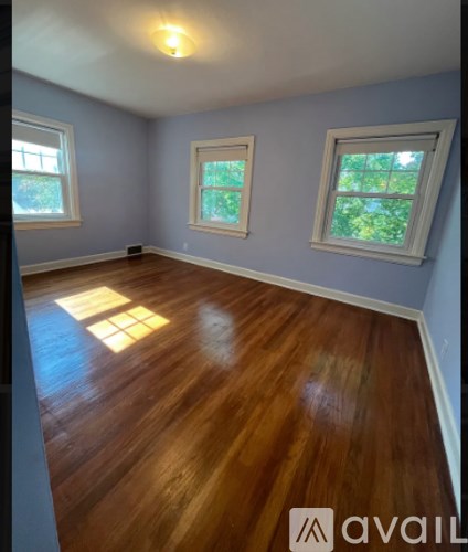 A room with wooden floors and three windows.