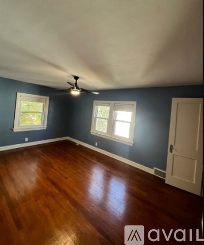 A room with a ceiling fan and two windows.