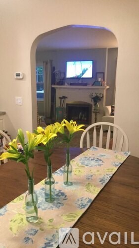 A table with a floral tablecloth and vases with yellow flowers on it.