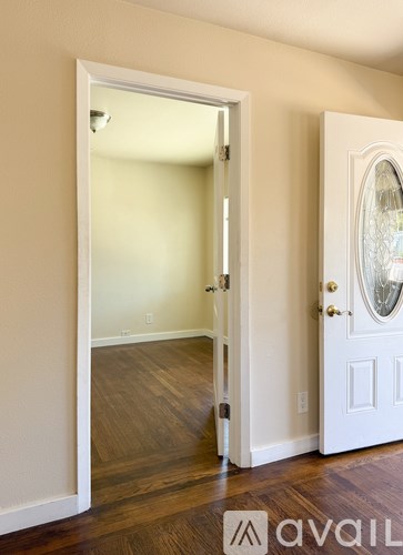 A white door is open to a room with wood floors.