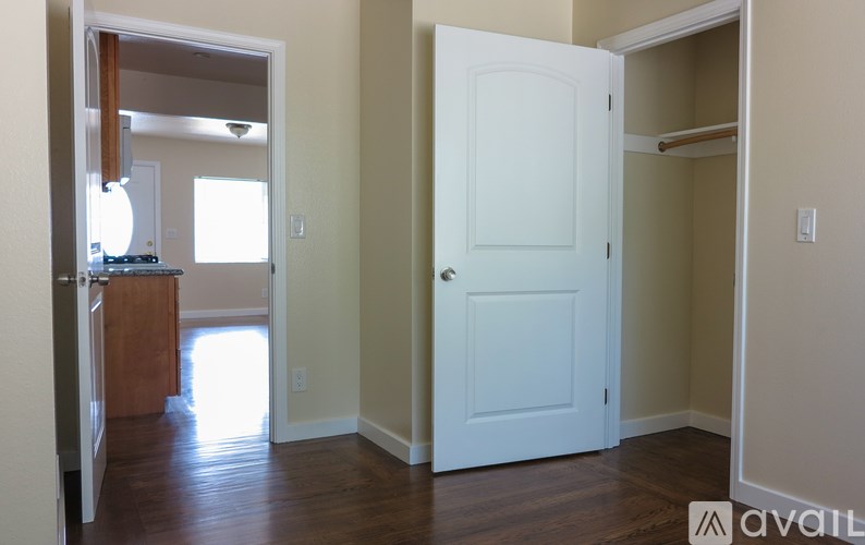 A white door is in the middle of a room with wood floors.