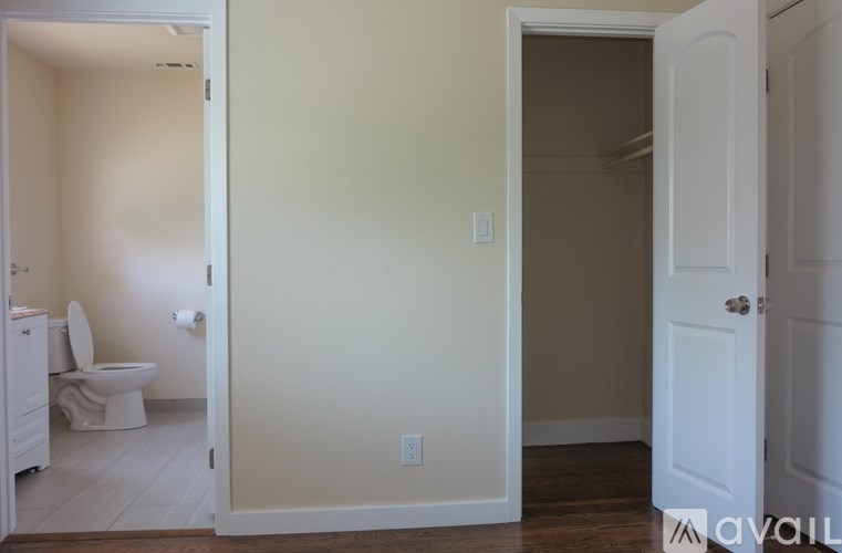 A bathroom with a toilet and a doorway leading to another room.