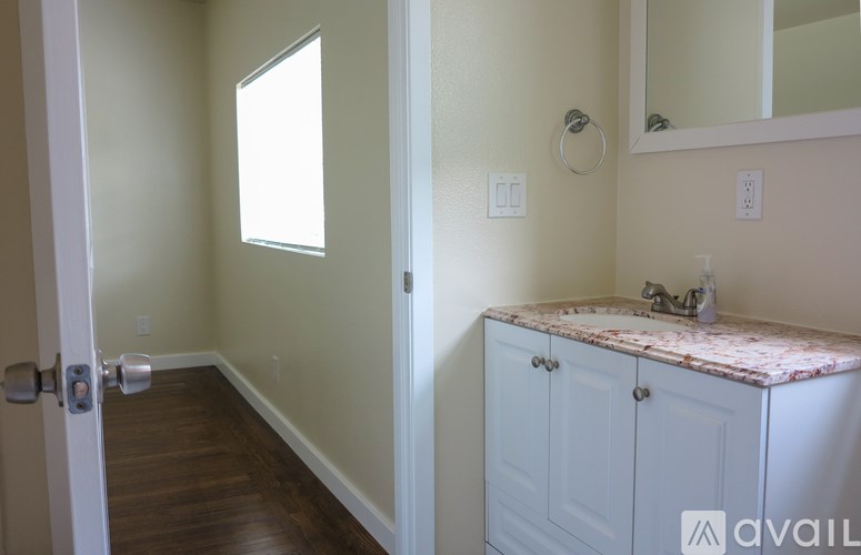 A bathroom with a marble countertop and a wooden floor.