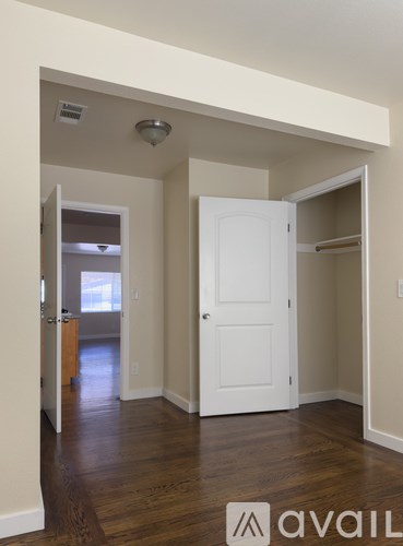 A room with a toilet and a door leading to a kitchen.