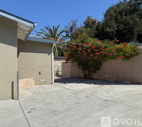 A house with a fence and a tree with red flowers.