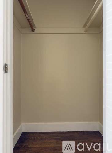 A small, empty room with a wooden floor and white walls.