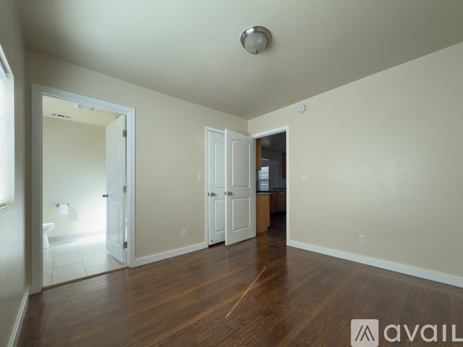 A spacious room with wooden floors and white walls.