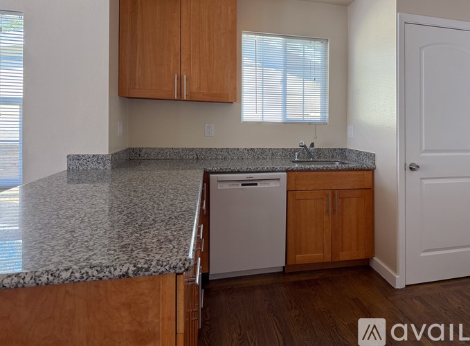 A kitchen with a granite countertop and wooden cabinets.
