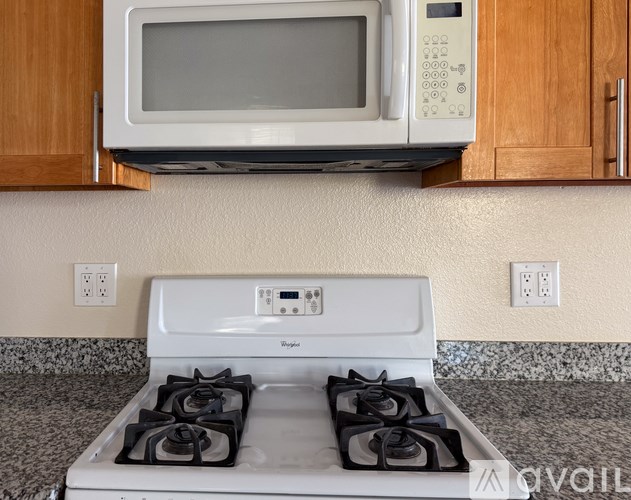 A white stove with four burners under a microwave.