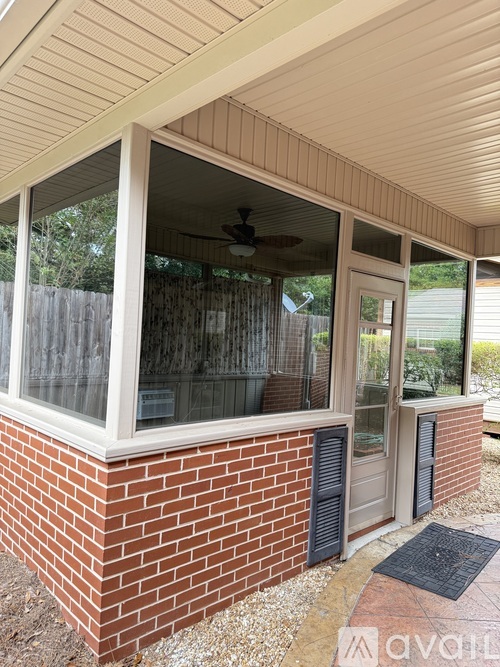 A house with a brick wall and a window with a fan.