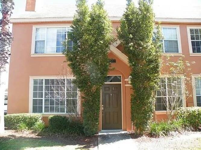 A house with a brown door and windows covered with white blinds.