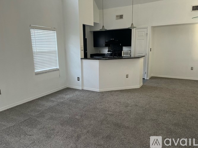 A spacious living room with a kitchenette in the background.