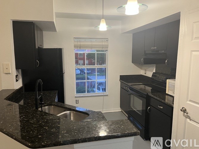 A kitchen with black cabinets and a black granite countertop.