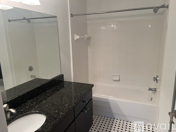 A bathroom with a black granite countertop and white tiles.