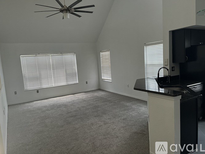 A room with a ceiling fan, carpeted floor, and a black cabinet.