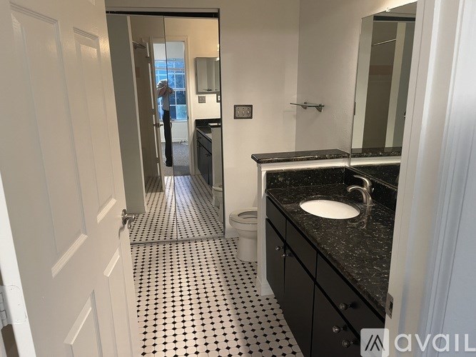 A bathroom with a sink, mirror, and a black and white tiled floor.