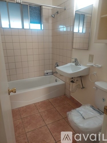 A bathroom with a tiled wall, a toilet, a sink, and a bathtub.