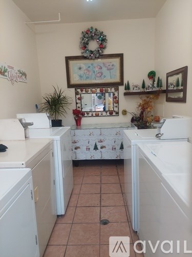 A small laundry room with a washer and dryer, a wreath on the wall, and a mirror with a Christmas theme.