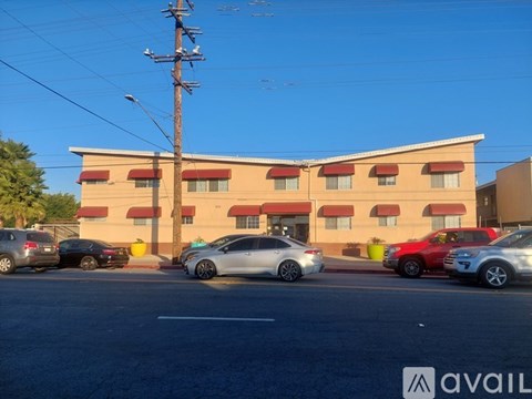 A parking lot with cars and a building with a red awning in the background.