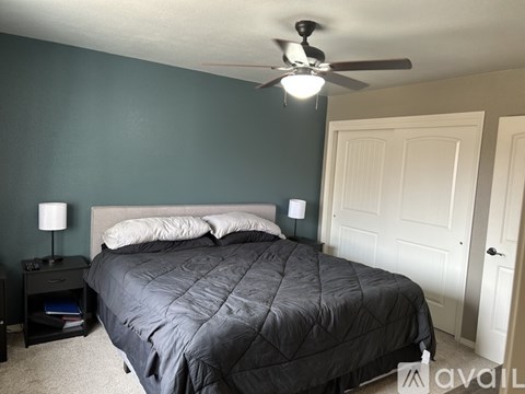 A bedroom with a bed, nightstand, and ceiling fan.